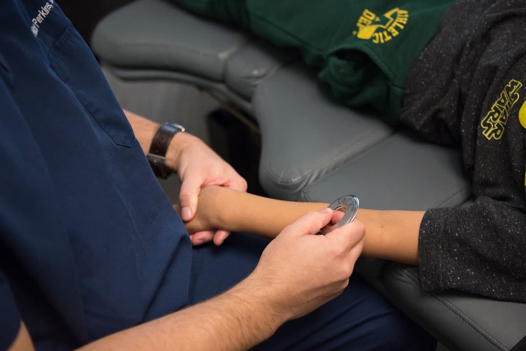 A licensed clinician examining a young athlete's wrist during a community care session